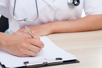 Health professional filling out paper form at desk